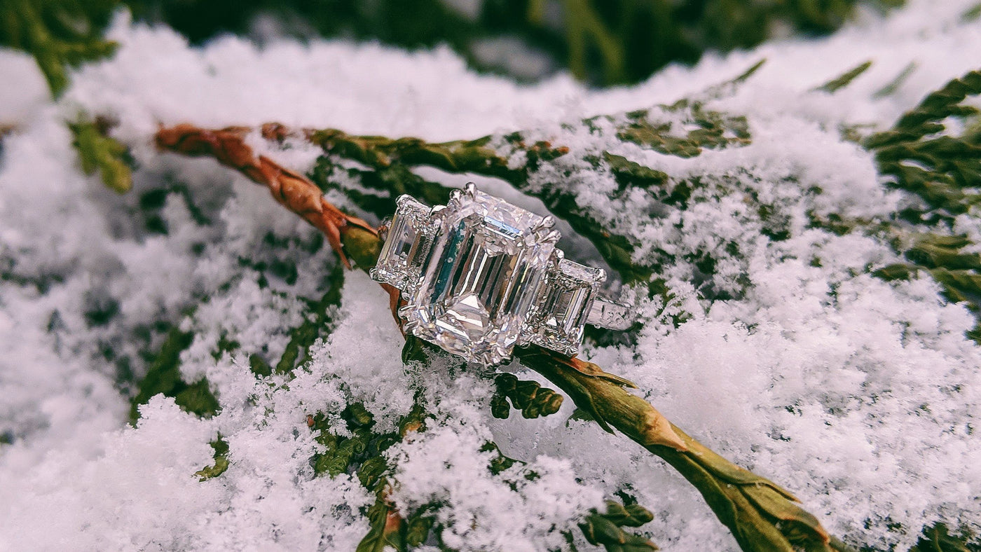 three stone diamond ring on snowy evergreen