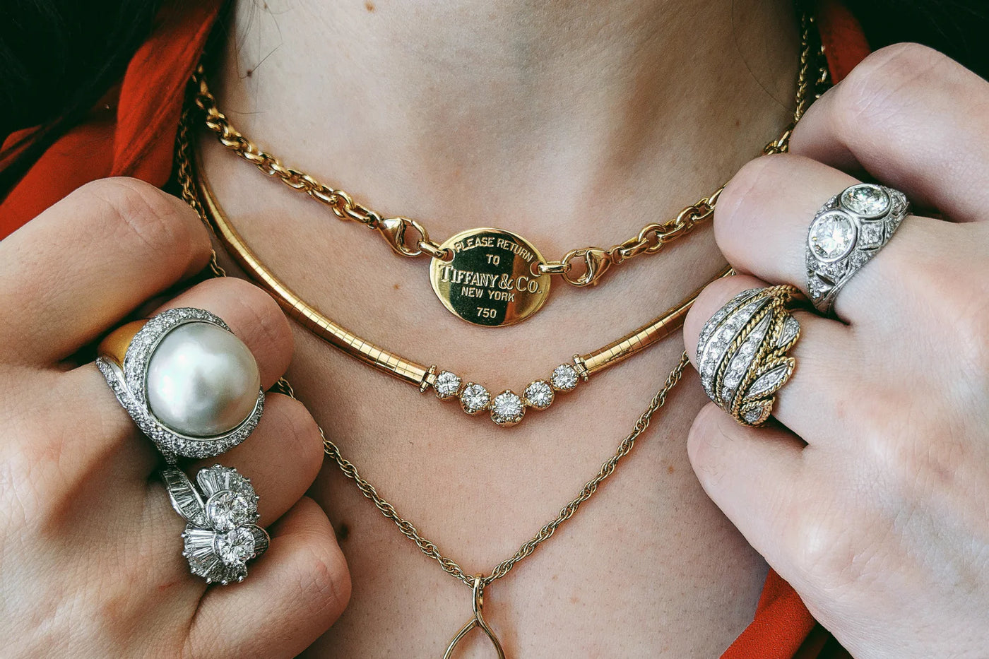 Close Up of Woman's Hands Wearing 2 Pearl and Diamond Vintage Rings on Each Hand up by her Neck with 3 Gold Necklaces